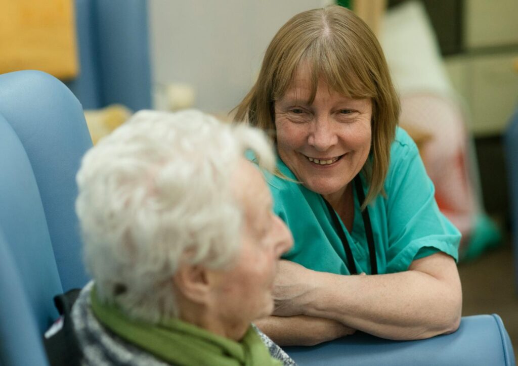 Woman in nurses uniform smiling at elderly lady