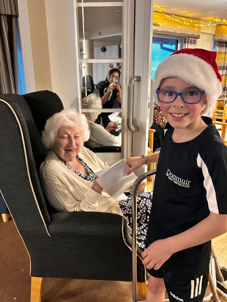 resident smiles while being given a handmade christmas card by a child