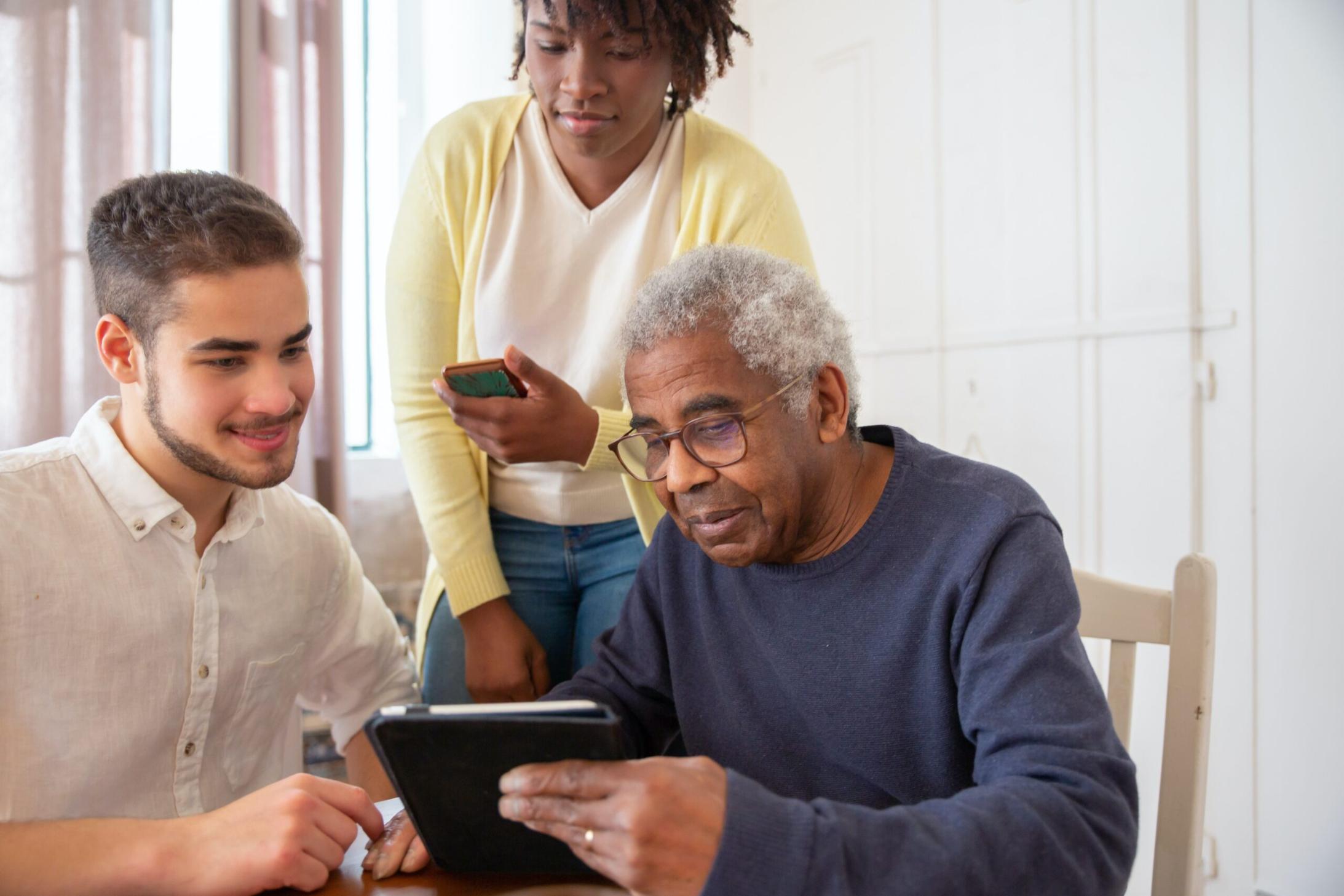 young man helping older couple use a tablet